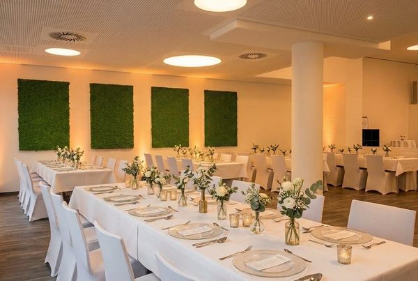 Eventlocation OCS Stuttgart: festlich gedeckte Tafeln mit Blumen vor grünen Moosbildern